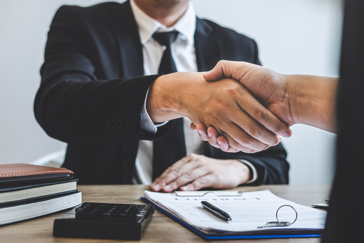 Cropped Hands Of Real Estate Agent Giving Handshake To Customer In Office